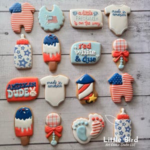 May include: A collection of patriotic-themed cookies, including ones shaped like a baby onesie with "made in america" text, a bib with an American flag, and a popsicle with red, white, and blue icing. Other cookies include the text "American Dude" and "a little firecracker is on the way".
