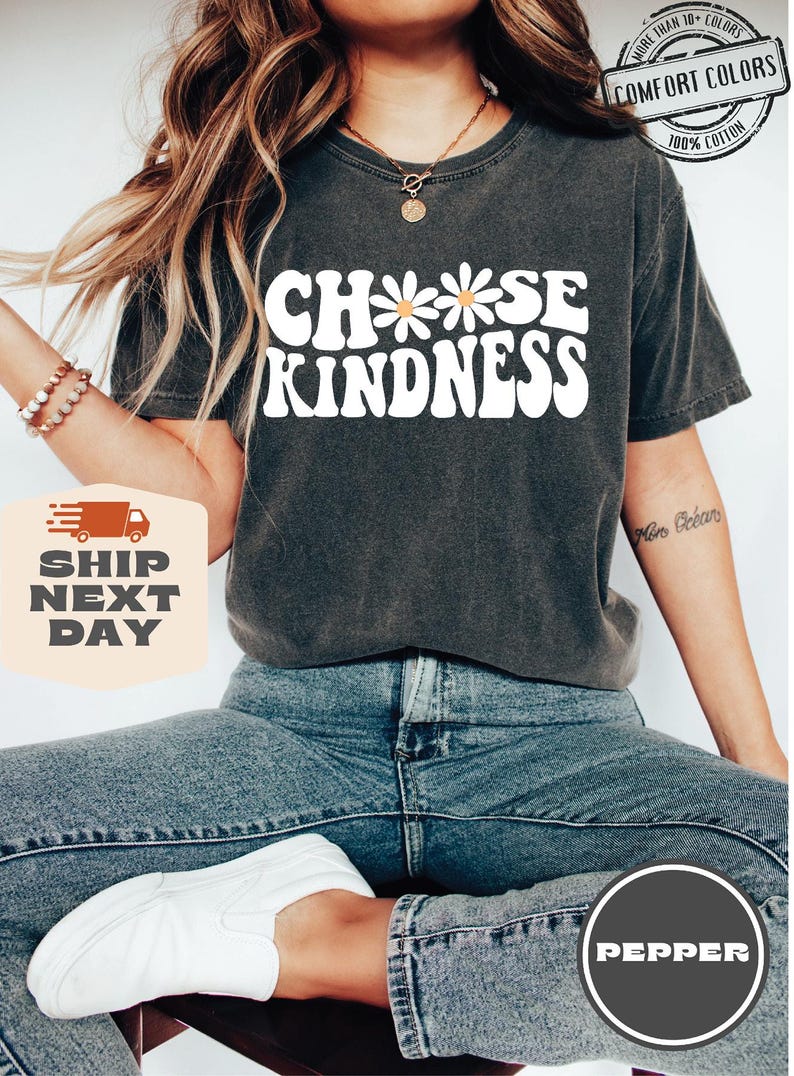 May include: A dark gray t-shirt with the text "Choose Kindness" in white with a daisy graphic. The shirt is made of 100% cotton.