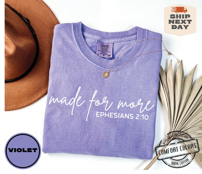 Puede incluir: Una camiseta morada con el texto "made for more" y "EPHESIANS 2:10" en blanco. La camiseta est&aacute; hecha de 100% algod&oacute;n.