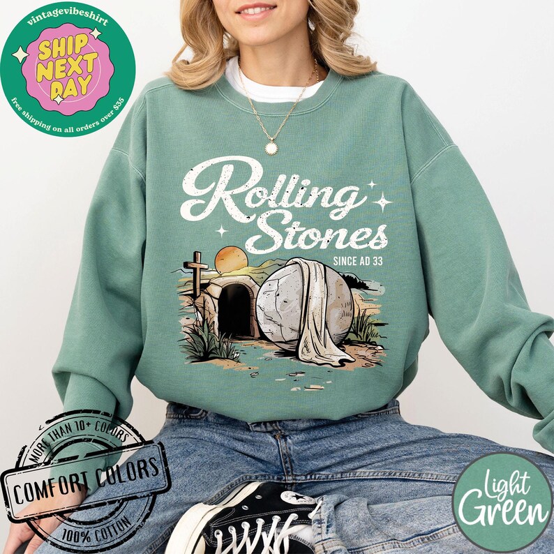 May include: A light green sweatshirt with a graphic of a stone rolling away from a tomb. The graphic includes the text "Rolling Stones Since AD 33".