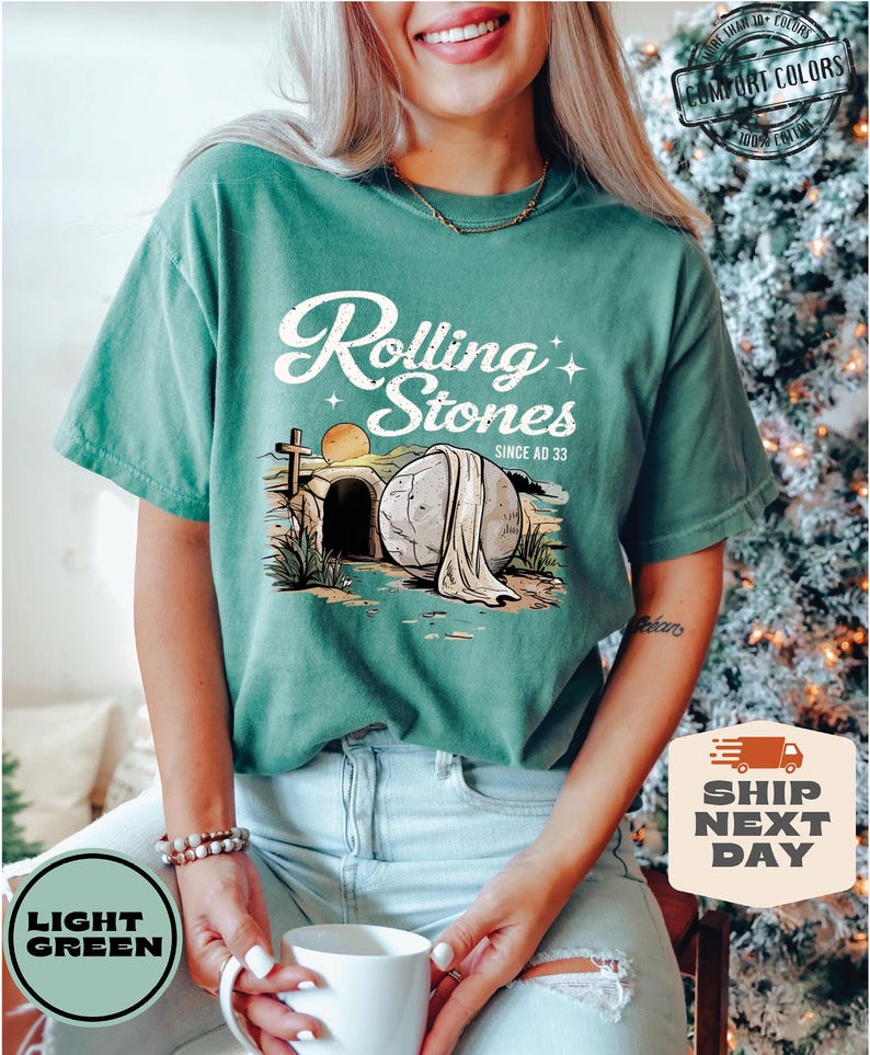 May include: A light green t-shirt with a vintage-style graphic of a stone tomb with a cross and the text "Rolling Stones Since AD 33".