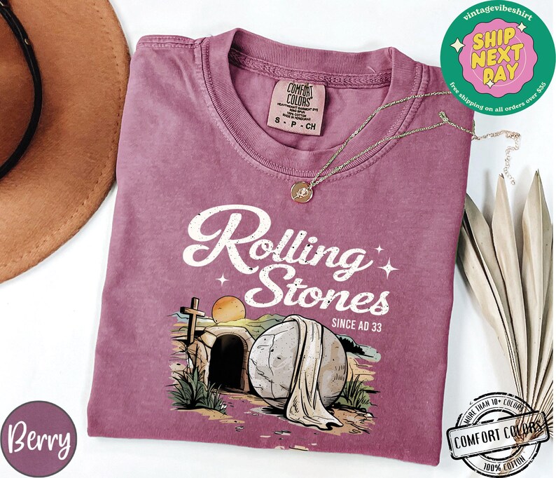 May include: A mauve t-shirt with a vintage-style graphic of a stone rolling away from a tomb. The graphic includes the text "Rolling Stones Since AD 33".