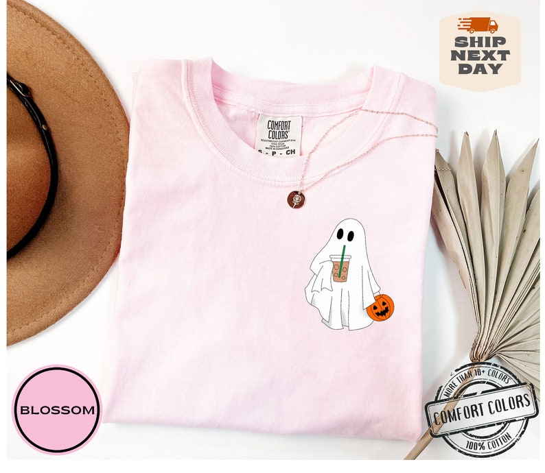 Peut inclure: T-shirt rose avec un fant&ocirc;me blanc tenant une citrouille et une tasse de caf&eacute;. Le t-shirt porte l'inscription "COMFORT COLORS" sur l'&eacute;tiquette.