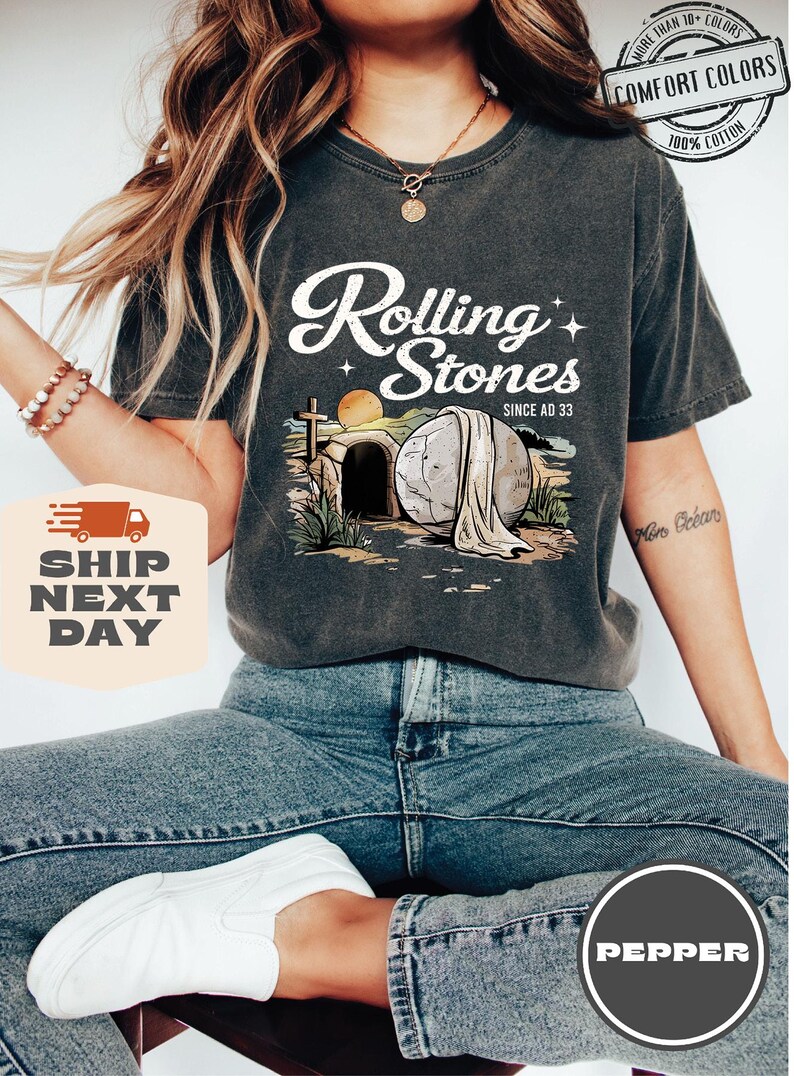 May include: A gray t-shirt with a graphic of a stone rolling away from a tomb. The graphic includes a cross, a sunrise, and the text "Rolling Stones Since AD 33".