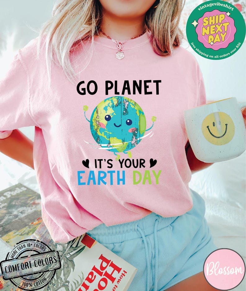 May include: Pink t-shirt with a cartoon image of the Earth holding up a heart with the text "Go Planet It's Your Earth Day".