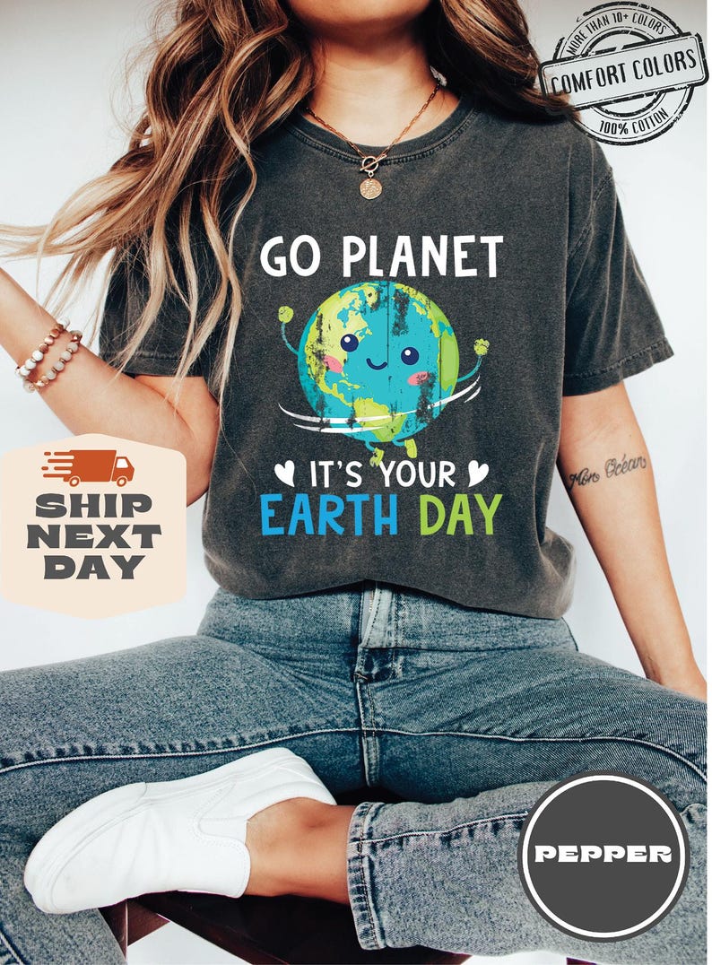 May include: A dark gray t-shirt with a cartoon image of the Earth holding a sign that says "Go Planet" and "It's Your Earth Day".