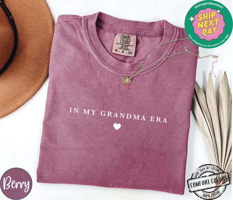 May include: A mauve colored t-shirt with the text "IN MY GRANDMA ERA" and a small white heart. The shirt is made of a soft, comfortable fabric.