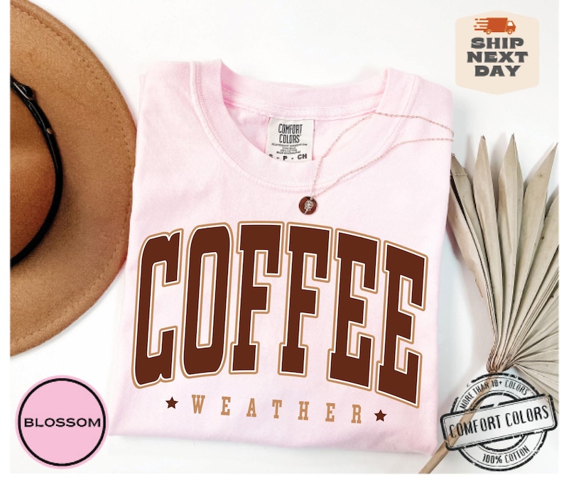 May include: Pink t-shirt with brown text that reads "COFFEE WEATHER" with a star on either side of the word "WEATHER".