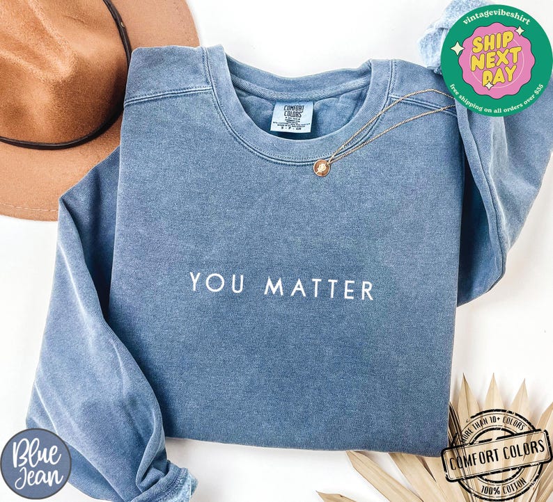 May include: A blue sweatshirt with the text "YOU MATTER" in white lettering. The sweatshirt is made of 100% cotton and is available in a variety of colors.