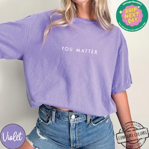 May include: A purple t-shirt with the text "YOU MATTER" printed in white on the front. The shirt is made of 100% cotton and is available in a variety of colors.