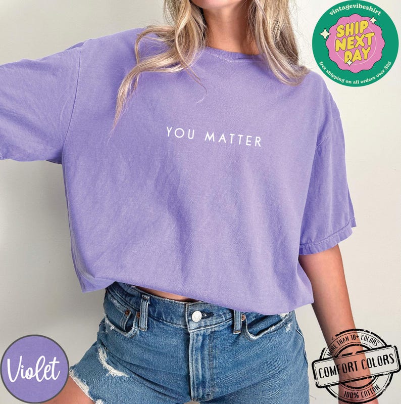 May include: A purple t-shirt with the text "YOU MATTER" printed in white on the front. The shirt is made of 100% cotton and is available in a variety of colors.