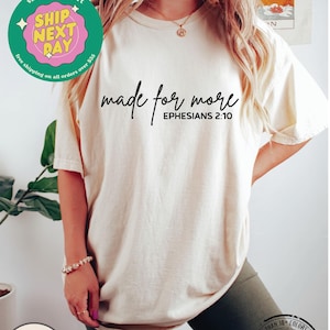 Puede incluir: Camiseta de color marfil con el texto "made for more" y "EPHESIANS 2:10" impreso en ella.
