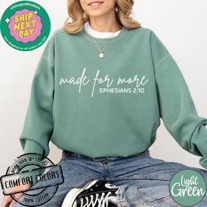 Puede incluir: Una sudadera de color verde claro con el texto "made for more" y "EPHESIANS 2:10" en blanco. La sudadera est&aacute; hecha de 100% algod&oacute;n y est&aacute; disponible en una variedad de colores.