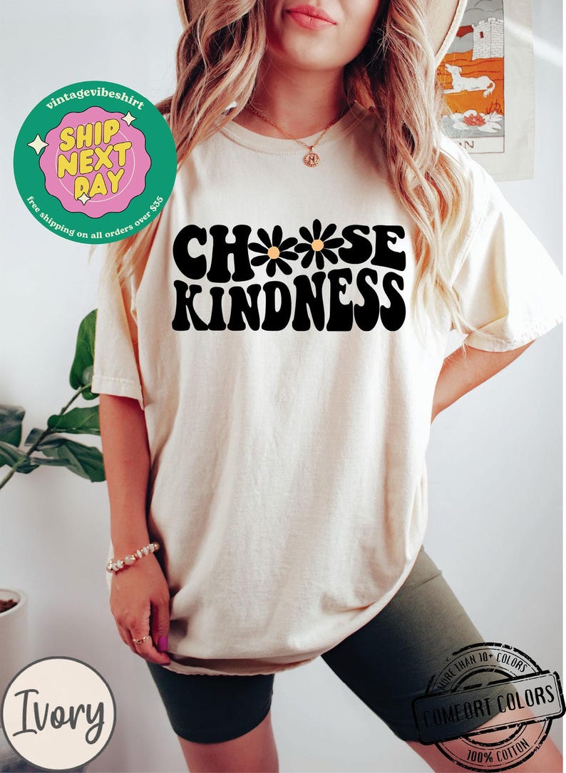 May include: A white t-shirt with the text "Choose Kindness" in black with three yellow daisies. The text is in a retro font style.