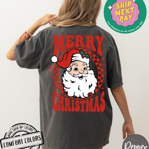 May include: A gray t-shirt with a red and white graphic of Santa Claus with the text "Merry Christmas" in red.