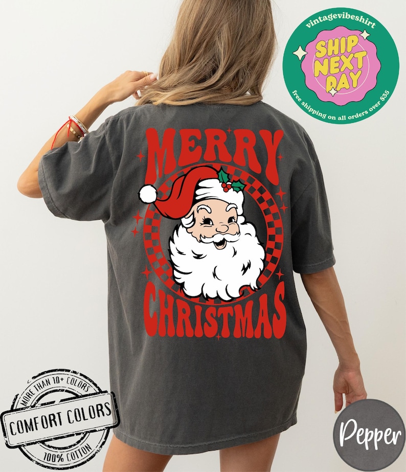 May include: A gray t-shirt with a red and white graphic of Santa Claus with the text "Merry Christmas" in red.
