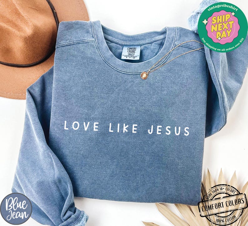 May include: A blue sweatshirt with the text "LOVE LIKE JESUS" in white lettering. The sweatshirt is made of a soft, comfortable fabric and has a relaxed fit.