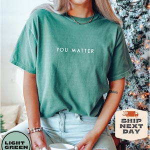 May include: A light green t-shirt with the text "YOU MATTER" printed in white on the front.