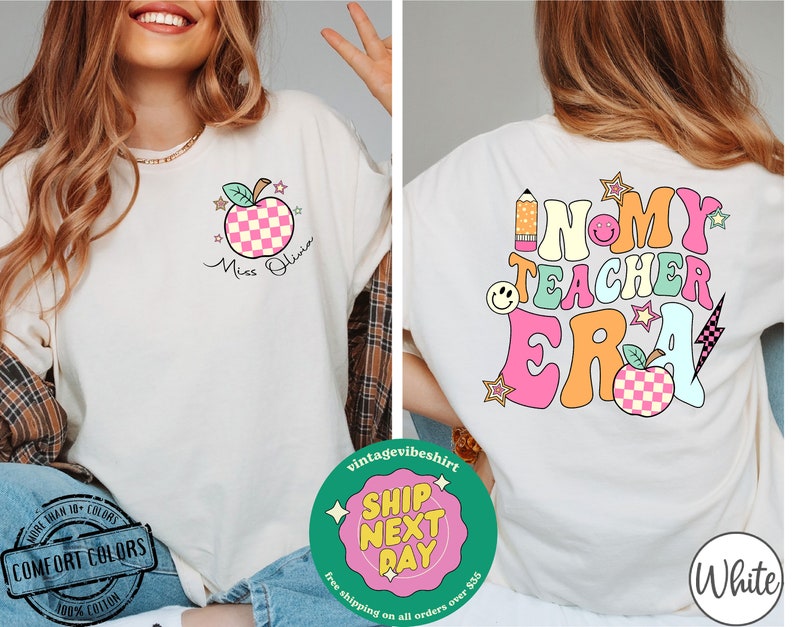K&ouml;nnte beinhalten: Wei&szlig;es T-Shirt mit einer pinkfarbenen und gr&uuml;nen Grafik, auf der "In My Teacher Era" mit einem roten Apfel, einem Bleistift und Sternen steht. Die Vorderseite des Shirts hat einen pinkfarbenen und wei&szlig;en karierten Apfel mit einem gr&uuml;nen Stiel und Bl&auml;ttern. Der Text "Miss Olivia" steht unter dem Apfel.