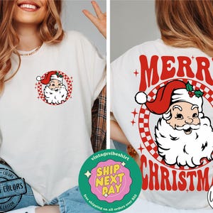 May include: White t-shirt with a red and white checkered circle design featuring a cartoon Santa Claus with the text "Merry Christmas" in red letters.