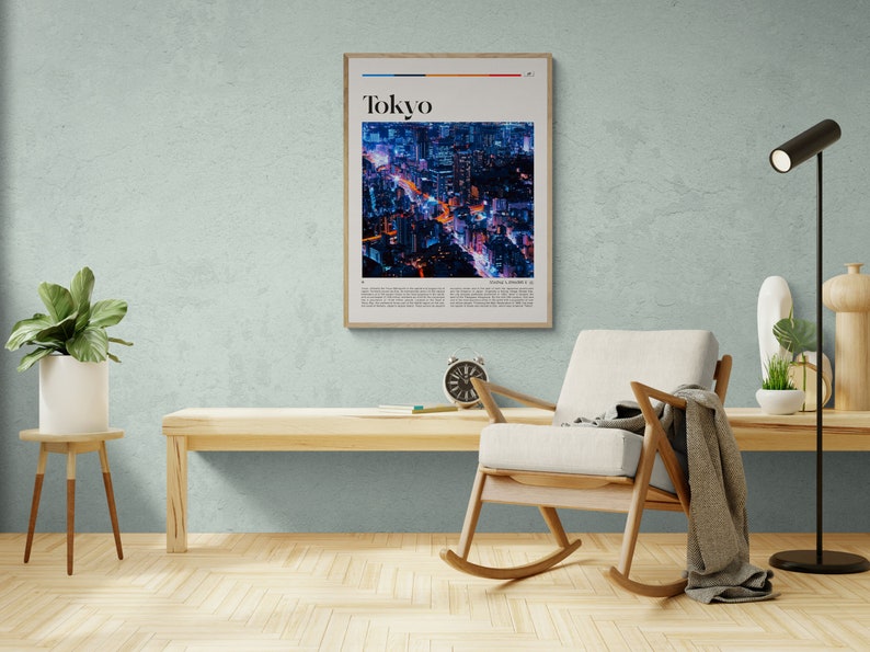 Może przedstawiać: Ramka z plakatem przedstawiającym zdjęcie nocnego panoramy miasta. Plakat zatytułowany jest "Tokyo" i ma białe tło z czarnym tekstem. Plakat wisi na jasnoniebieskiej ścianie nad drewnianym fotelem bujanym.