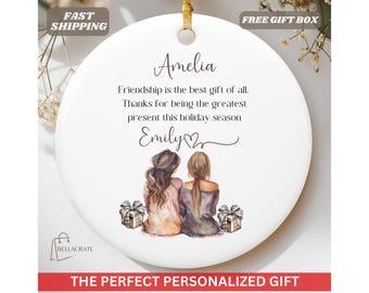 May include: White ceramic ornament with a watercolor illustration of two women holding gifts. The ornament has the text "Amelia Friendship is the best gift of all. Thanks for being the greatest present this holiday season Emily"
