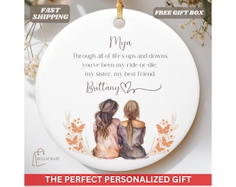 May include: White ceramic ornament with a personalized message for a sister and best friend. The message reads "Mya, Through all of life's ups and downs, you've been my ride-or-die. My sister, my best friend. Brittany". The ornament features a watercolor illustration of two women with long brown hair.