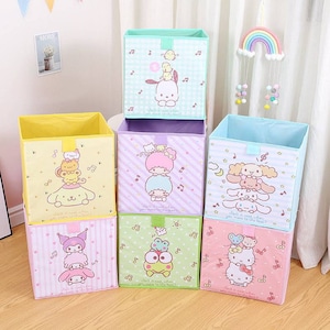 May include: Seven colorful, foldable storage cubes with cartoon character designs. Each cube features a different character, including Hello Kitty and Keroppi, with musical notes and the text "Isn't it neat when you meet to be the best?"