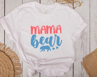 May include: White t-shirt with the text "mama bear" in pink and blue lettering. A blue bear silhouette is below the text with two small blue hearts.