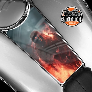 May include: A gas tank decal featuring a hooded figure engulfed in flames. The decal has the text "Bad Daddy Garage" in a circle with a motorcycle graphic.