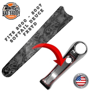 May include: A motorcycle part set, including a long, patterned piece with a skull design and a chrome-finished component. The text reads "FITS 2000 - 2007 SOFTAIL DEUCE FXSTD" and "MADE IN THE USA". The image features a red arrow.