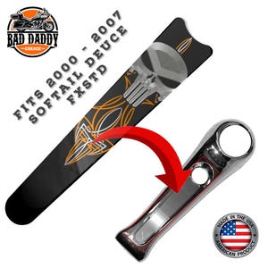 May include: Black motorcycle part with a silver skull design and orange pinstripes. The text "FITS 2000 - 2007 SOFTAIL DEUCE FXSTD" is printed on the part. A chrome-finished motorcycle part is also shown. The product is made in the USA.