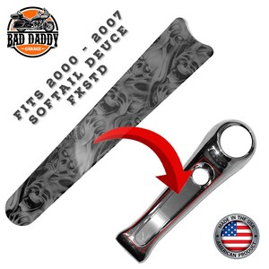 May include: A motorcycle part with a skull design and the text "FITS 2000 - 2007 SOFTAIL DEUCE FXSTD". The part is black and gray with a chrome accent. The image also includes the "BAD DADDY GARAGE" logo and "MADE IN THE USA AMERICAN PRODUCT" text.