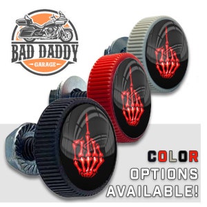 May include: Three motorcycle bolt covers with a red skeleton middle finger design. The bolt covers are available in black, red, and gray.