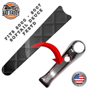 May include: A motorcycle part with a chrome finish and a black diamond-patterned section. The text reads "FITS 2000 - 2007 SOFTAIL DEUCE FXSTD" and "MADE IN THE USA". The Bad Daddy Garage logo is also visible.