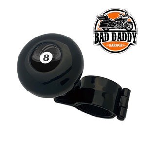 May include: Black steering wheel knob with a black and white 8-ball design. The knob is attached to a black clamp. The text "BAD DADDY GARAGE" is visible in the background.
