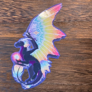 May include: A black dragon with rainbow wings and a glowing orb in its hand. The dragon is depicted in a stylized, almost stained glass-like design.