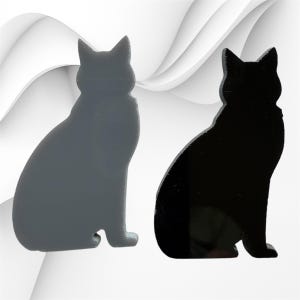 May include: Two cat-shaped silhouettes standing side by side. One figure is a solid matte gray, while the other is a solid glossy black. Both cat shapes feature pointed ears and a seated posture, presented as flat, cutout-style decorative items.