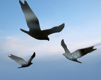 May include: Three metal bird silhouettes in flight against a blue sky. The birds have textured surfaces and are in various positions, suggesting movement. The artwork evokes a sense of freedom and nature.