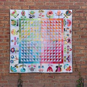 Peut inclure: Une courtepointe colorée avec un motif géométrique de triangles dans des tons de rose, orange, jaune et bleu. La courtepointe est entourée d'une bordure de motifs floraux fantaisistes dans diverses couleurs et motifs.