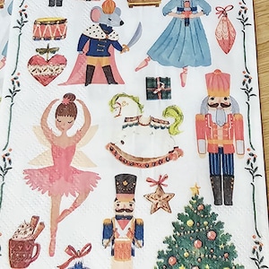 May include: White paper napkins with colorful illustrations of Christmas and holiday themes. The designs include nutcrackers, a Christmas tree, a ballerina, and a clock. The napkins are decorated with a floral border.