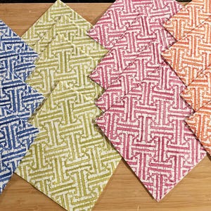 May include: Four fabric swatches with a geometric pattern. The swatches are in blue, green, pink, and orange.