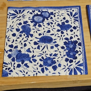 May include: Blue and white floral patterned paper napkins with a blue border.