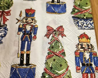 Puede incluir: Fondo blanco con un patrón repetido de soldados cascanueces, árboles de Navidad y plantas en maceta. Los soldados cascanueces llevan uniformes azules y rojos con detalles dorados. Los árboles de Navidad están decorados con cintas rojas. Las plantas en maceta están en macetas de cerámica azul y blanca.