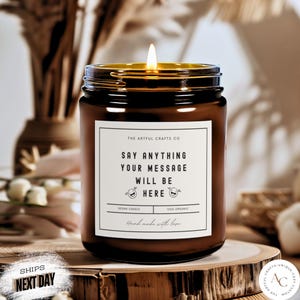 May include: A brown glass candle jar with a white label that says "The Artful Crafts Co. Say Anything Your Message Will Be Here Vegan Candle 100% Organic Hand Made with Love".