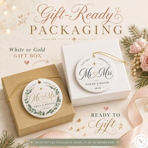 May include: Two round white ceramic ornaments with gold string, one featuring a green eucalyptus wreath design and the other a minimalist star motif. Both ornaments are printed with the text Mr & Mrs, names, and dates, displayed on brown and white gift boxes.