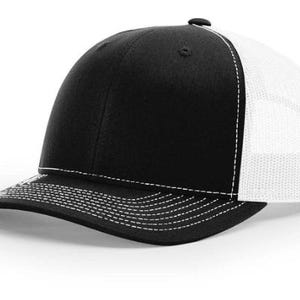 Puede incluir: Gorra de camionero negra y blanca con visera curva. Los paneles frontales y la visera son negros, mientras que los paneles laterales y traseros son de malla blanca. Costuras blancas acentúan la visera y las costuras.
