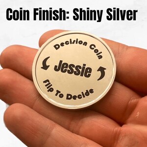 May include: Shiny silver decision coin with the text "Decision Coin" and "Flip To Decide" around the edge. The name "Jessie" is in the center of the coin.