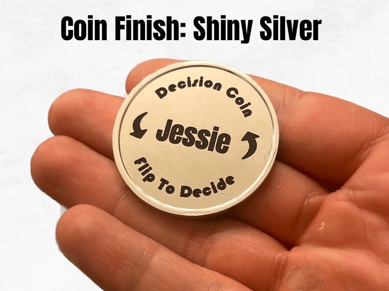 May include: Shiny silver decision coin with the text "Decision Coin" and "Flip To Decide" around the edge. The name "Jessie" is in the center of the coin.