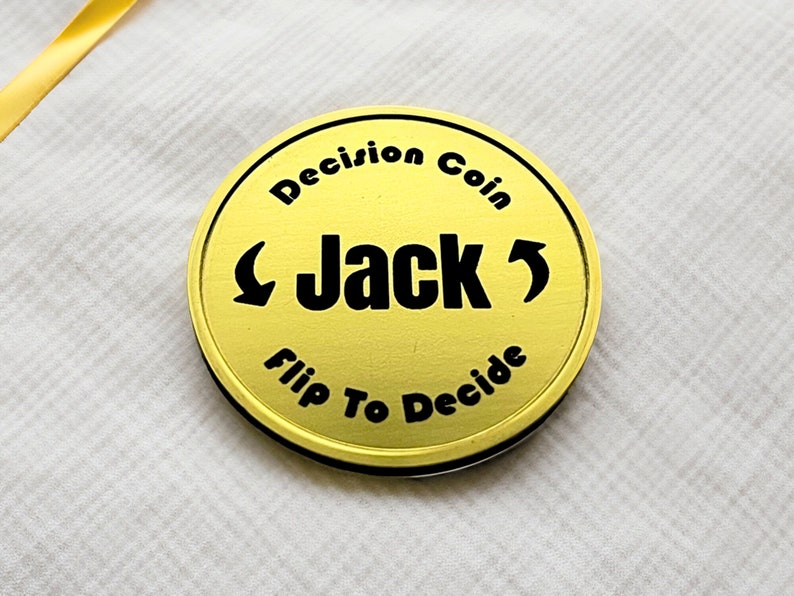 May include: A gold-colored coin with the text "Decision Coin" and "Flip To Decide" around the edge. The word "Jack" is in the center with arrows pointing left and right.